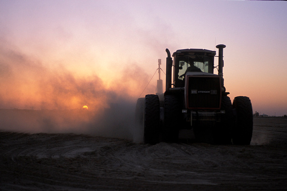 Tractor working ground a sunset with dust cloud  Georgic Odyssey project - Photograph by Edwin Remsberg